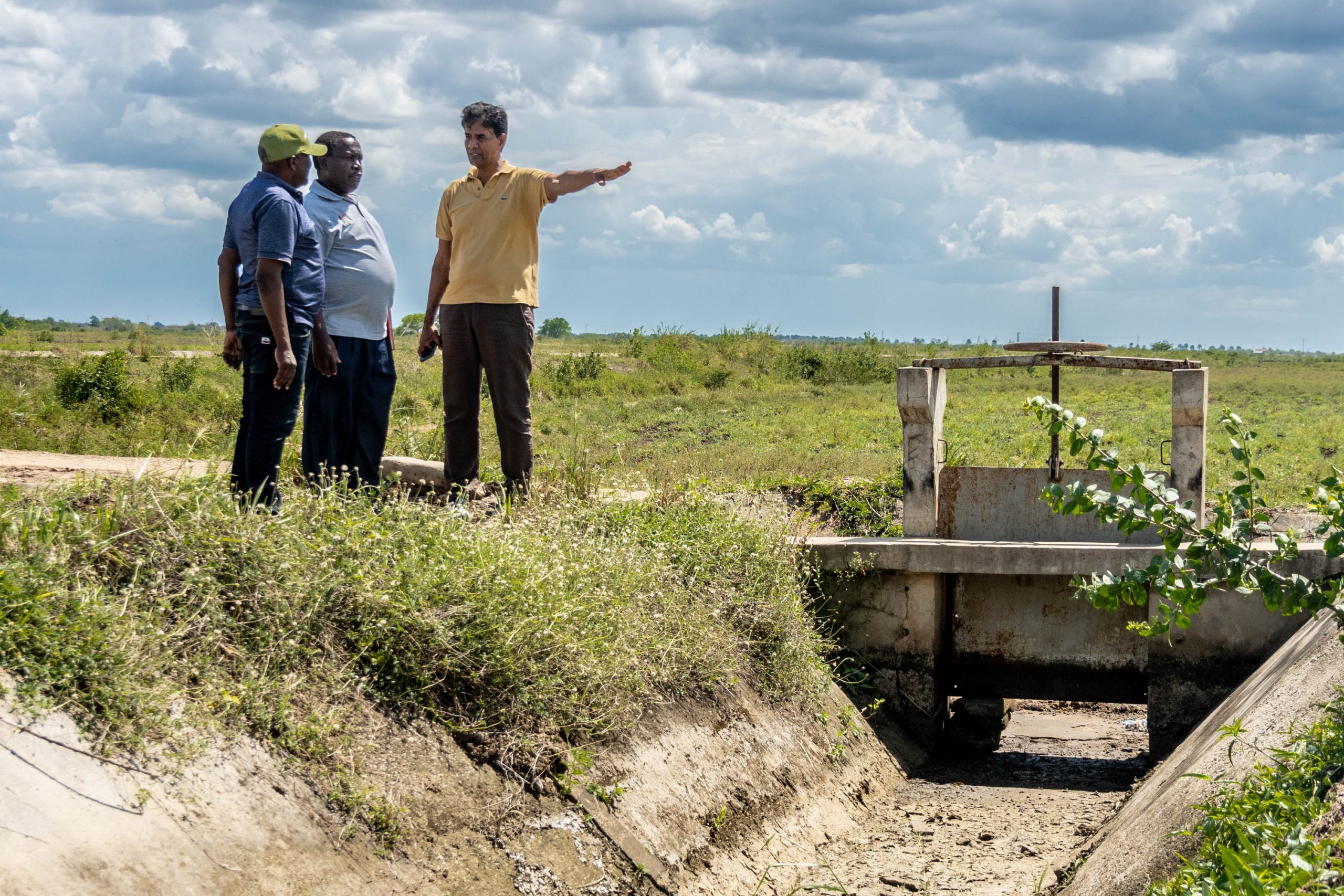 Three people standing by irrigation channel in Tanzania